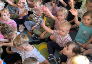 Dzieci pozują do zdjęcia podczas koncertu unosząc ręce do góry