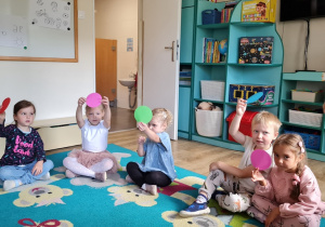 Dzieci trzymają kolorowe koła z origami w górze