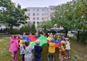 Zabawy z chusta animacyjną i piłeczkami w ogrodzie przedszkolnym