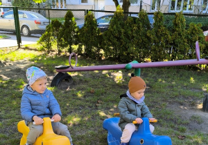Chłopcy kołyszą się na bujakach w ogrodzie przedszkolnym