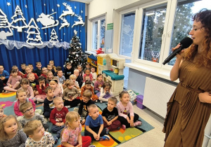 Pani z mikrofonem śpiewa dzieciom piosenkę