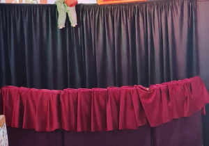 Scena teatralna, na której znajduje się lalka i skrzynia