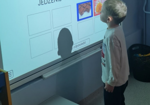 Dziecko rozwiązuje zadanie edukacyjne na tablicy multimedialnej