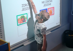 Dziecko rozwiązuje zadanie edukacyjne na tablicy multimedialnej