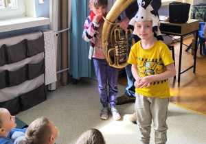 Dziewczynka dmucha w ustnik, chłopiec ma na głowie czapkę byka