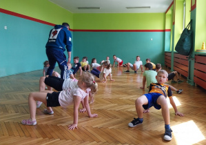 Dzieci wykonują ćwiczenia na sali gimnastycznej